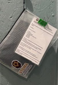 Emergency stoma pack hanging from a hook in the wall of a toilet.