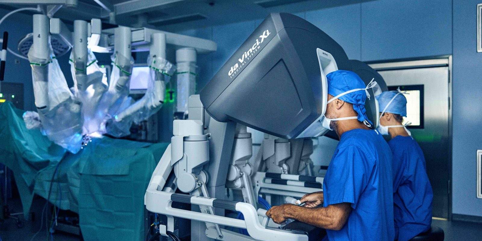 Surgeons using robotic equipment in operating theatre