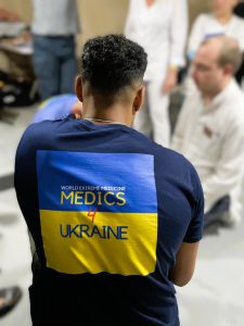 A man stands with his back to the camera in a 'Medics4Ukraine' T shirt