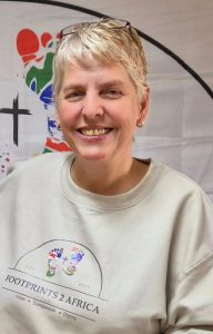 Sam Yiollaris, a lady with short grey hair, smiles at the camera