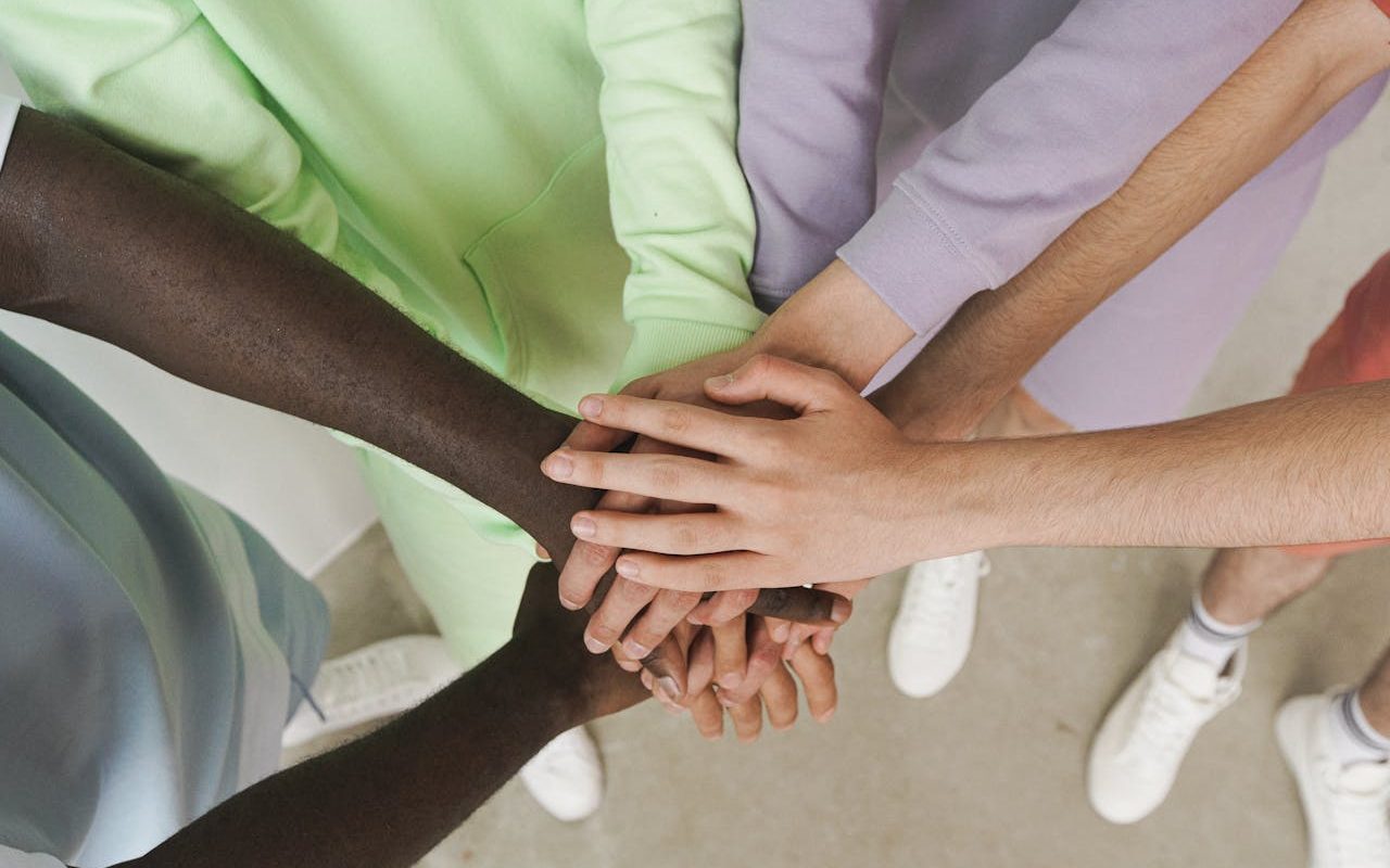 Different hands stacked on top of each other to signify team work. Different skin colours.