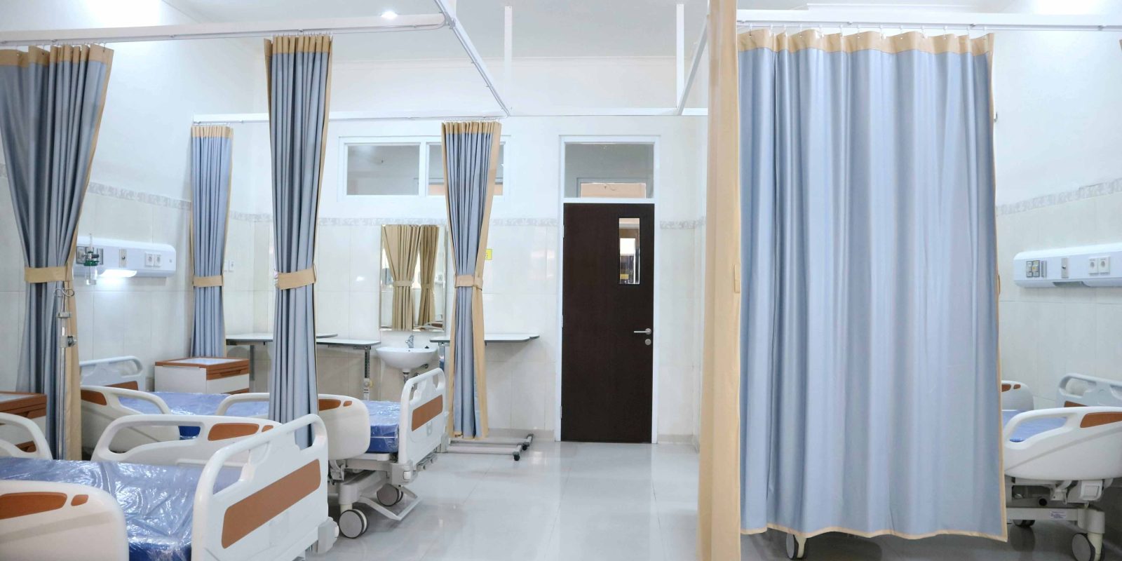 An empty hospital ward looking towards a closed door.