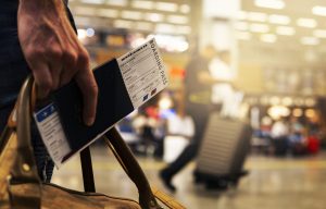 Action shot of airport. Close up of a man's hand carrying bag, passport and flight ticket.