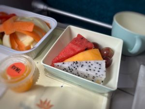 In-flight food: trays of fruit on the seat table.