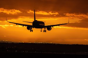 Plane landing at sunset. An orange sky and the rear view silhouette of the plane.