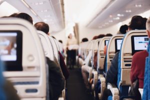 View down the aisle of a plane cabin with the people seated with their backs to camera.