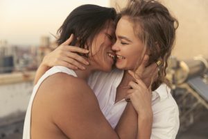 Two smiling women embrace.