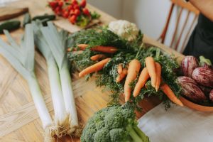 Vegetables on a kitchen table including leeks, carrots and broccoli