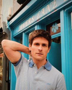 Singer-songwriter Tom Speight poses in a T-shirt outside a bar called 'Lovers Lane'.