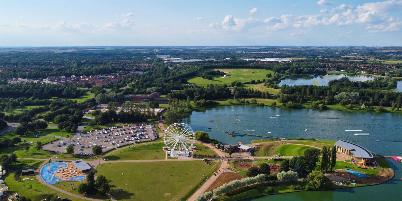 Stunning aerial shot of Milton Keynes showcasing a Ferris wheel, lakes, and surrounding greenery.